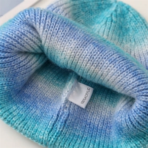 Detail shot of the 100% acrylic blue gradient tie-dye knitted beanie texture and tag