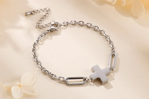 Macro shot of silver stainless steel cross pendant bracelet with scattered dried petals