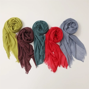 Detail showing five assorted cotton linen scarves in olive, red, and blue with fringe edges