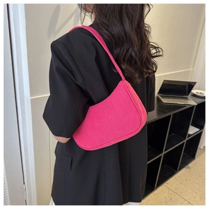 Close-up of pink corduroy baguette bag held by a model in a black blazer