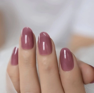 Gros plan sur des ongles adhésifs rose poudré avec une finition gelée translucide brillante