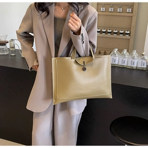 Close-up of khaki leather tote bag with white stitching in a cafe setting