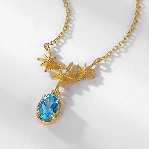 Detail of S925 silver necklace with golden starfish pendants and blue topaz gemstone
