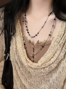 Detail of layered beaded necklace with black beads and hollow floral silver pendant