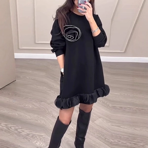 Détails de broderie rose blanche et ourlet à volants sur une robe noire à manches longues