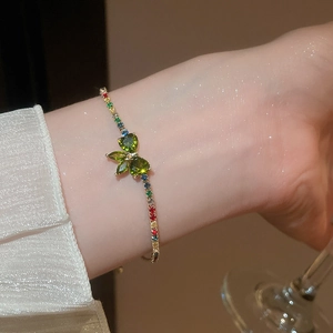 Detailed shot of a gold bracelet featuring a green zircon butterfly and rainbow crystals