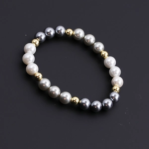 Macro view of multi-color shell pearl bracelet with elegant gold beads on black background