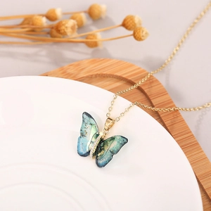 Detail of butterfly necklace featuring blue-green gradient wings with gold foil and crystals