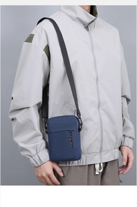 Detail of dark blue canvas crossbody bag with adjustable shoulder strap worn by model