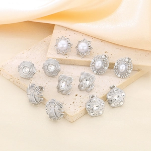 Geometric crystal stud earring set with silver base and pearls on a stone plate