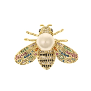Detailed macro view of a golden bee brooch with colorful crystals and a white pearl