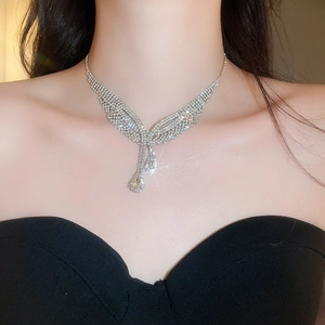 Detail der silbernen Strasshalskette mit Flügeldesign und Tropfenanhänger am Model