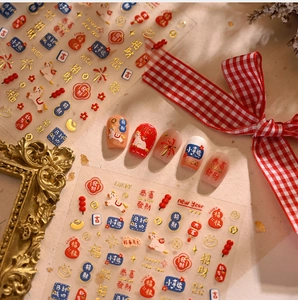 Close-up of Chinese New Year nail stickers with fortune cats and festive lantern designs