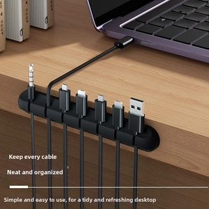 Detailed view of black 7-slot silicone cable manager holding various USB cords on desk