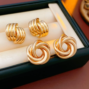 Detail of gold geometric earrings showing woven loop and knot flower designs on cushion