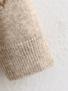 Close-up of oatmeal chunky knit texture and ribbed cuff detail on women sweater