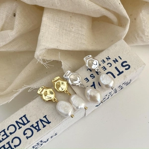 Detailed close-up of irregular Baroque pearl earrings in gold and silver finish