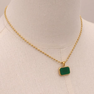 Close-up of green tiger eye stone pendant with gold bead chain on a neutral mannequin