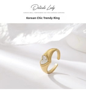 Detailed close-up of golden heart-shaped shell inlay ring on white textured surface