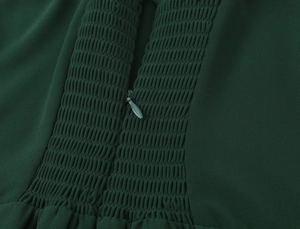 Detailed view of dark green smocking fabric with hidden zipper and textured finish