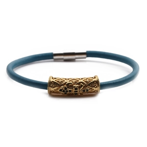 Detail of navy blue braided leather bracelet with gold carved tube and magnetic silver clasp