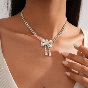 Detail of silver double-layered necklace with rhinestone bow and teardrop tassels
