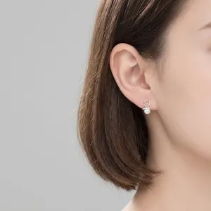 Elegant S925 silver knot earrings with white pearls on a model for a chic style