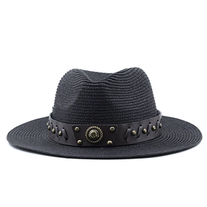 Close-up of black straw cowboy hat featuring a leather band with rivets and metal badge