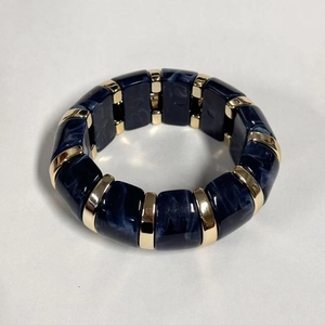 Détail de blocs de résine marbrée bleu foncé et d'entretoises dorées sur un bracelet