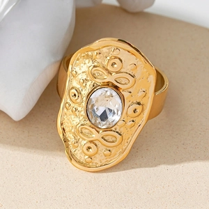 Vintage golden hammer textured ring with an oval crystal on a white ceramic stand