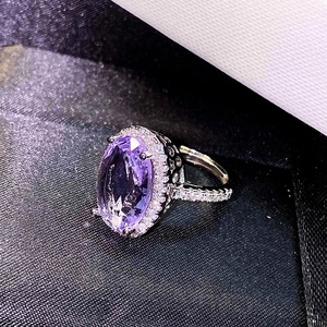 Macro shot of an oval purple amethyst ring with a sparkling halo and adjustable silver band