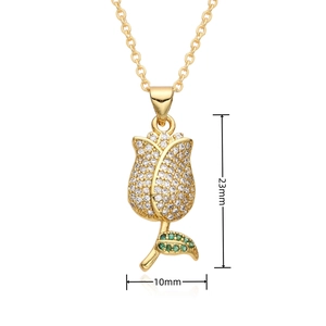 Macro detail of gold plated brass tulip pendant featuring clear and green cubic zirconia