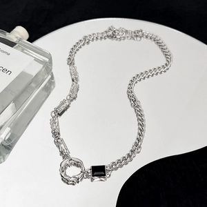 Dettaglio della collana in acciaio al titanio con pietra nera su superficie a specchio