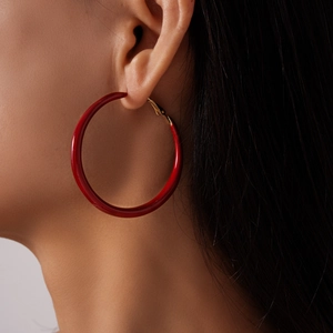Détail de créoles géométriques en résine rouge portées par un modèle en vue de profil minimaliste