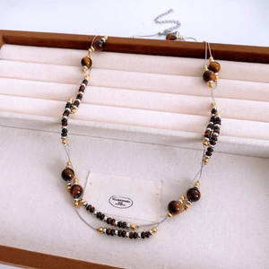 Close-up of double-layer necklace with tiger eye beads and gold accents on tray