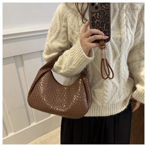 Detailed view of brown woven leather shoulder bag styled with a white knit sweater