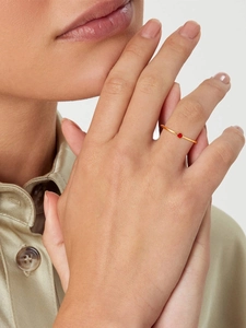 Detail of a slim gold ring featuring a brilliant red zircon gemstone on a model hand