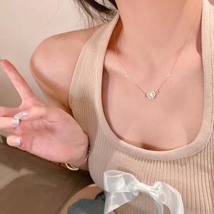 Dettaglio della collana con ciondolo a cuore alato e madreperla su una modella