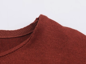 Détail de l'encolure en maille haute densité montrant les coutures du haut rouge foncé