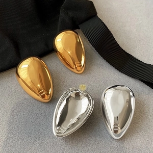 Minimalist polished metal teardrop earrings in gold and silver finish on a modern backdrop