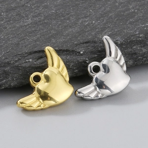 Close-up of gold and silver heart-shaped angel wing pendants on a dark rock surface