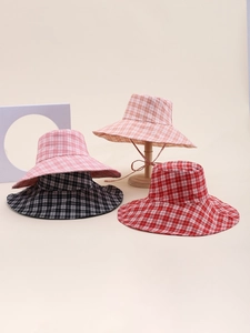 Detail of checkered sun hats in pink, black, red, and orange with adjustable chin straps