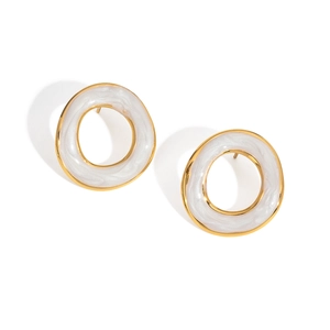 Détail macro de boucles d'oreilles créoles dorées avec texture marbre blanc incrustée