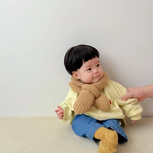 Close-up of brown chunky knit cross scarf on a baby model for winter warmth
