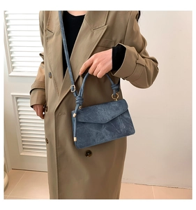Détail du sac bandoulière bleu à texture denim avec poignée nouée et boucles dorées
