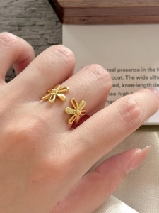 Detail of gold open ring with dual flower design worn on hand with lifestyle background