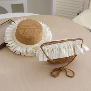 Close-up of woven straw hat and matching bag set with white satin ribbon detailing