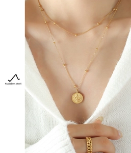 Detail of 18k gold double layered stainless steel necklace with evil eye coin pendant