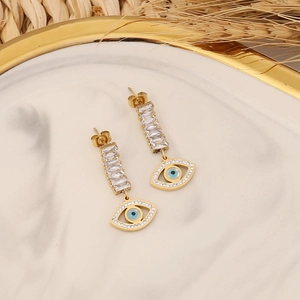 Detail of gold evil eye earrings with rectangular zircon crystals on marble tray