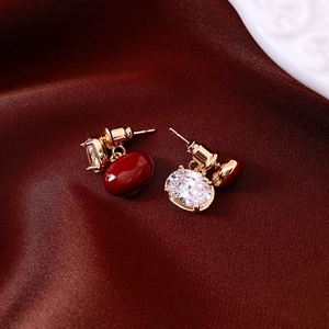 Gros plan de boucles d'oreilles ovales rouges plaquées or avec zircon sur soie